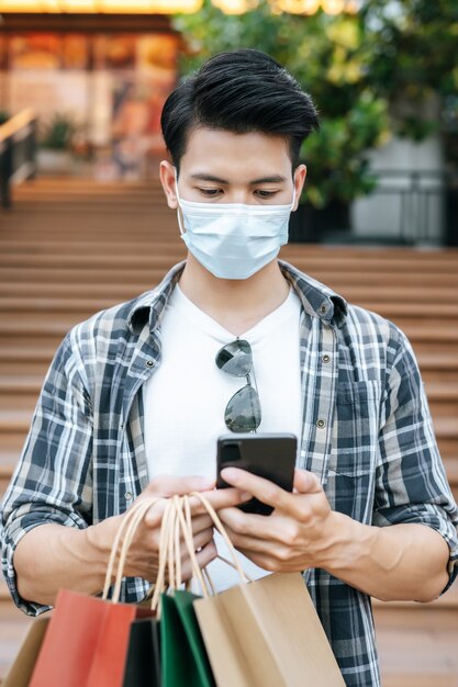 Portrait Young handsome man in protection mask holding paper bag