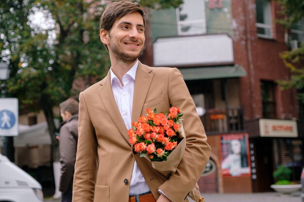 Portrait of young handsome man smiling holding a bunch of roses