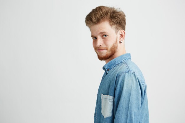 Portrait of young handsome man smiling looking turning to camera.