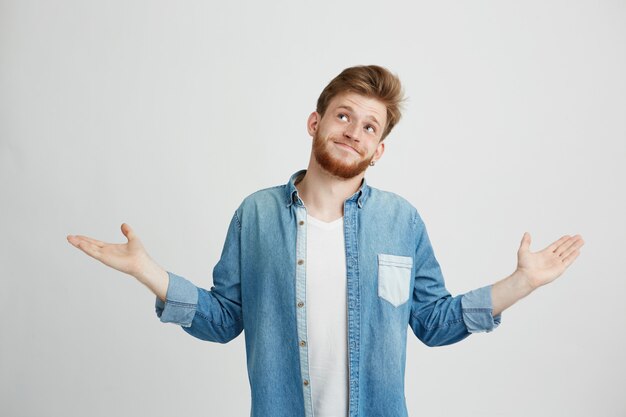 Portrait of young handsome man smiling looking up shrugging.