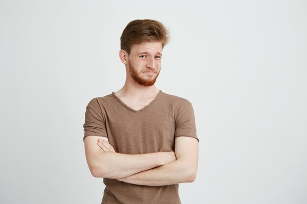 Portrait of young handsome man with beard with contempt crossed arms.