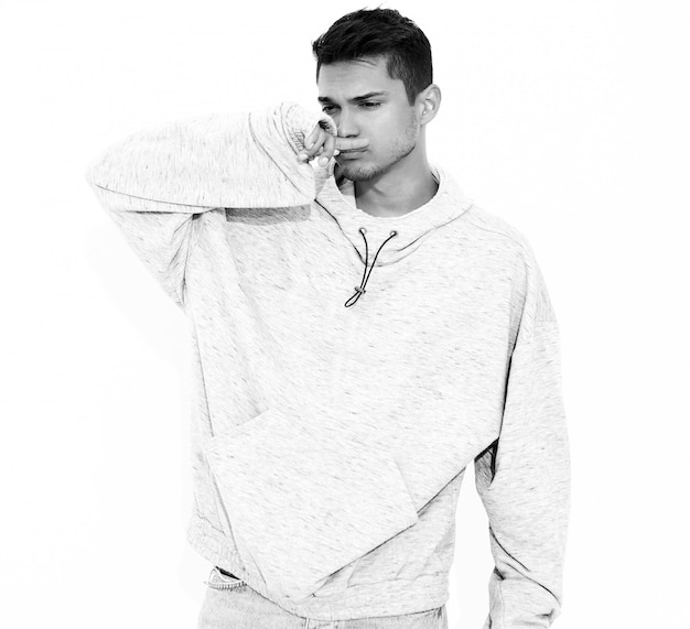 Portrait of young handsome model man dressed in gray casual hoodie clothes posing on white wall. Isolated