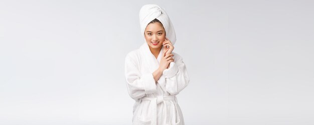 흰색 배경에서 목욕 가운을 입은 젊은 행복한 아시아 여성의 초상화