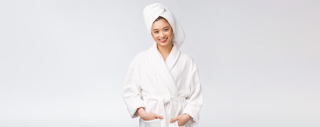 흰색 배경에서 목욕 가운을 입은 젊은 행복한 아시아 여성의 초상화