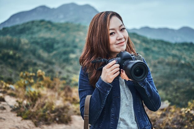 사진 카메라와 함께 젊은 행복 한 아시아 여자의 초상화. 그녀는 아름다운 자연을 만끽하며 사진 촬영을 준비하고 있습니다.