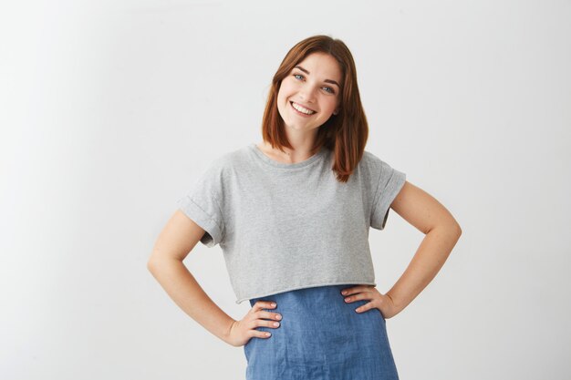 Portrait of young happy beautiful girl smiling with arms akimbo .