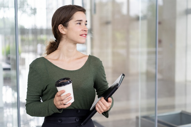 Portrait of young happy businesswoman with coffee and folder