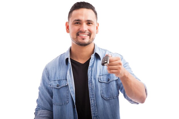 Портрет молодого счастливого человека, держащего ключи от своей новой машины на белом фоне