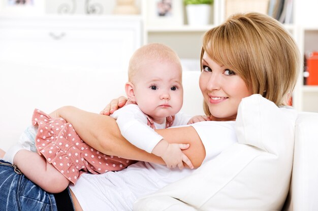 Portrait of young happy mother with newborn baby at home