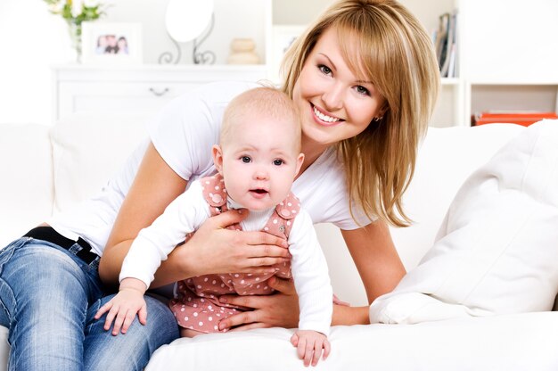 Portrait of young happy mother with newborn baby at home