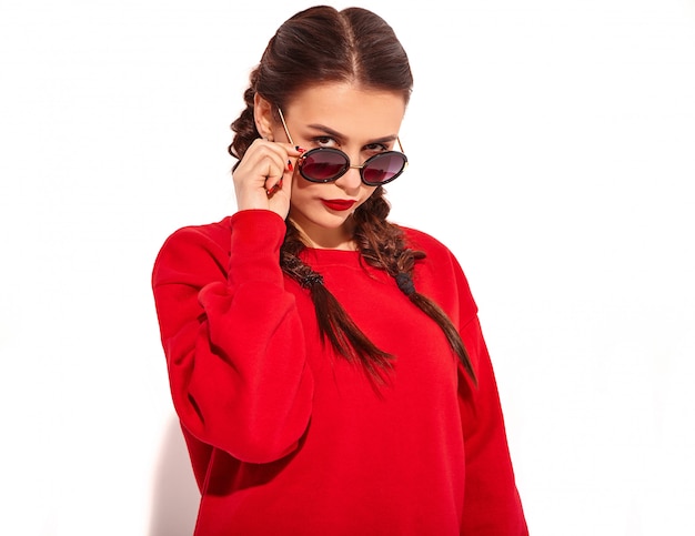 Portrait of young happy smiling woman model with bright makeup and colorful lips with two pigtails and sunglasses in summer red clothes isolated. Behind fashion sunglasses