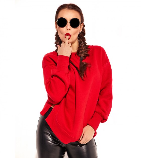 Portrait of young happy smiling woman model with bright makeup and colorful lips with two pigtails and sunglasses in summer red clothes isolated. Licking middle finger, fuck off sign