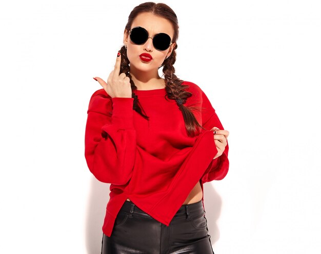 Portrait of young happy smiling woman model with bright makeup and colorful lips with two pigtails and sunglasses in summer red clothes isolated. showing fuck off sign
