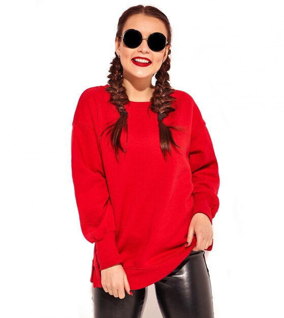 Портрет молодой счастливой усмехаясь модели женщины с ярким составом и красочных губ с 2 отрезками провода и солнечных очков в изолированных одеждах лета красных.