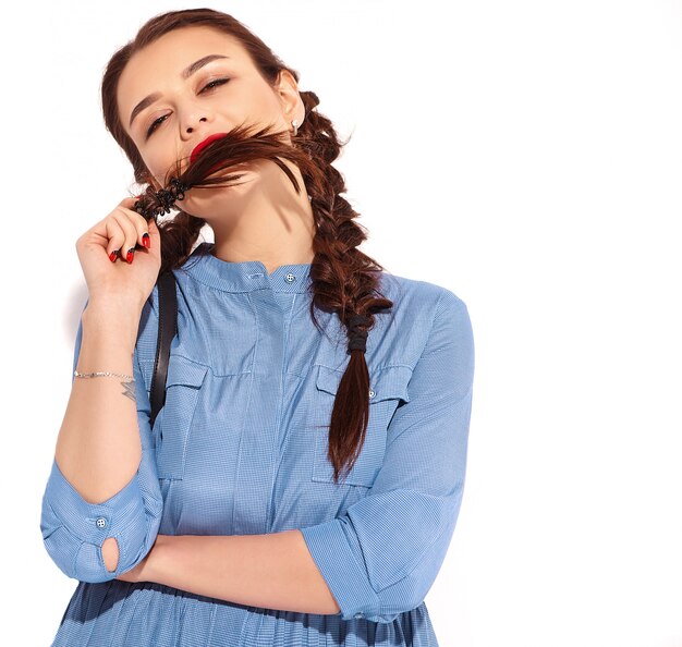 Portrait of young happy smiling woman model with bright makeup and red lips with two pigtails in hands in summer colorful blue dress