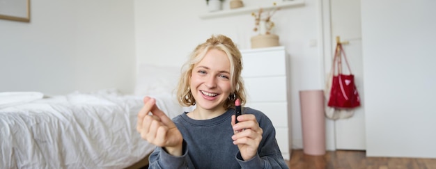 Portrait of young happy woman content media creator recording a vlog about makeup in her room using