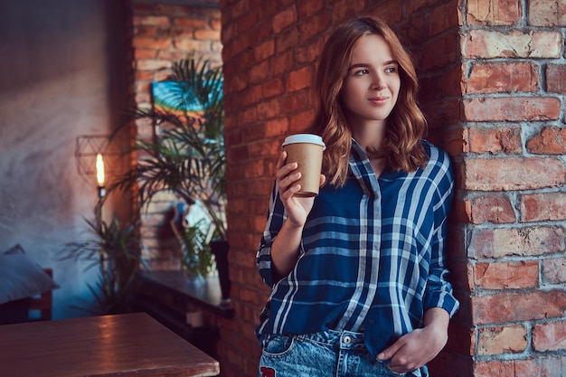 Portrait of a young hipster girl drinks morning coffee leaning a