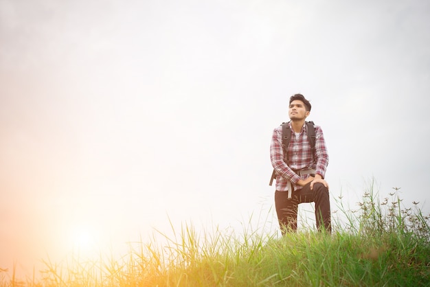 Portrait of young hipster man outdoor raising hands with backpac