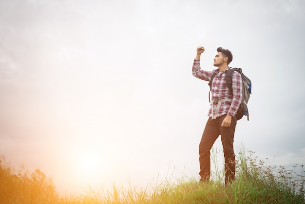 Portrait of young hipster man outdoor raising hands with backpac