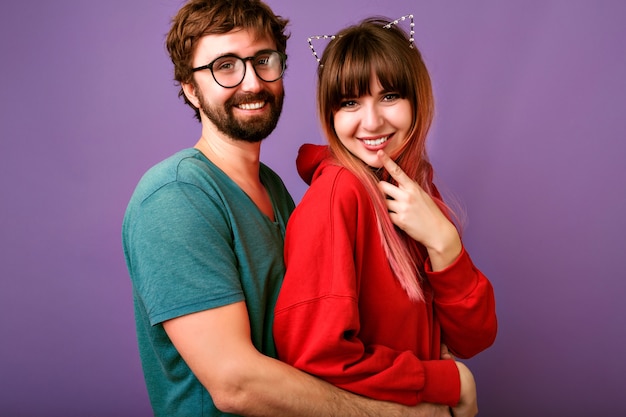 portrait of young hipster pretty family couple hugs, wearing trendy casual outfits, boyfriends and girlfriends, relation goals, violet wall