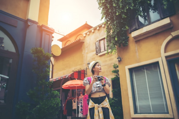 Portrait of young hipster woman backpack traveling taking photo in urban. 