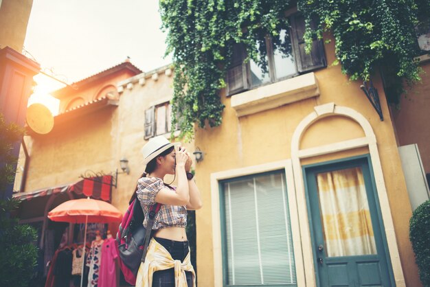 Free photo portrait of young hipster woman backpack traveling taking photo in urban.