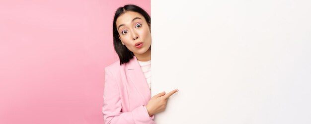 Portrait of young japanese business woman corporate lady in suit pointing on wall with chart showing