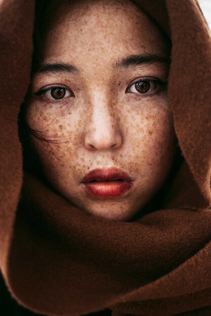갈색 담요로 덮여 주근깨가있는 젊은 카자흐어 여성의 초상화