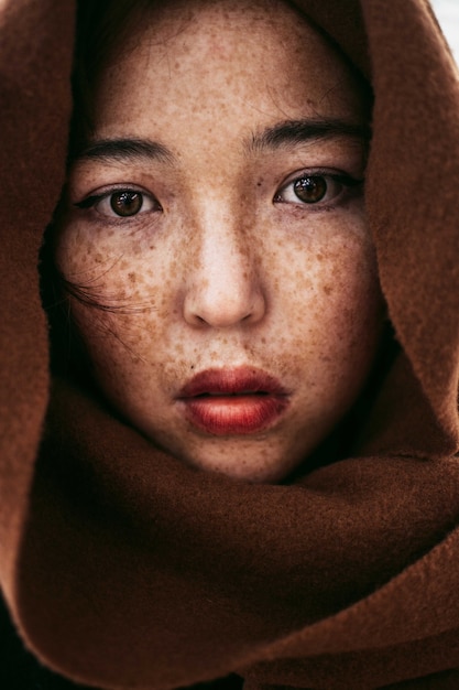 茶色の毛布で覆われたそばかすのある若いカザフ女性の肖像画