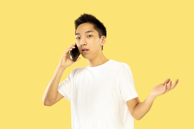 Portrait of young Korean man isolated on yellow studio.