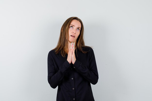 Portrait of young lady holding hands in praying gesture