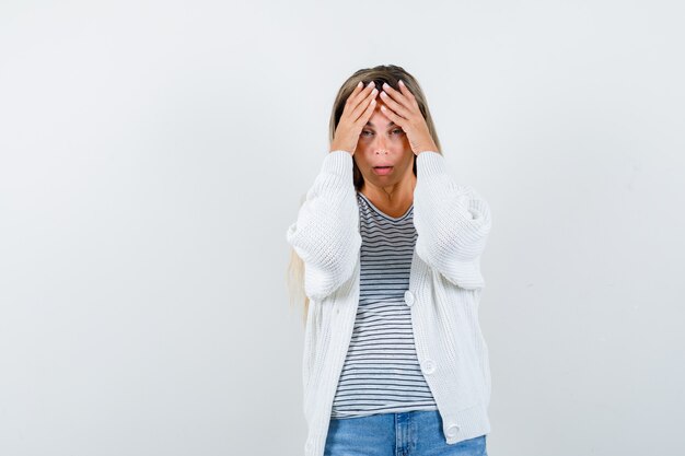 Portrait of young lady keeping hands on head in t-shirt, jacket and looking wistful front view