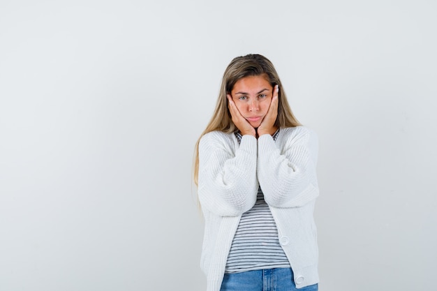 Portrait of young lady pillowing face on her hands in t-shirt, jacket and looking distressed front view