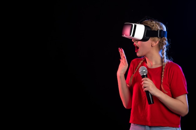 Portrait of young lady playing vr and singing on dark wall