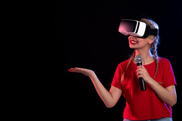 Portrait of young lady playing vr and singing on dark wall