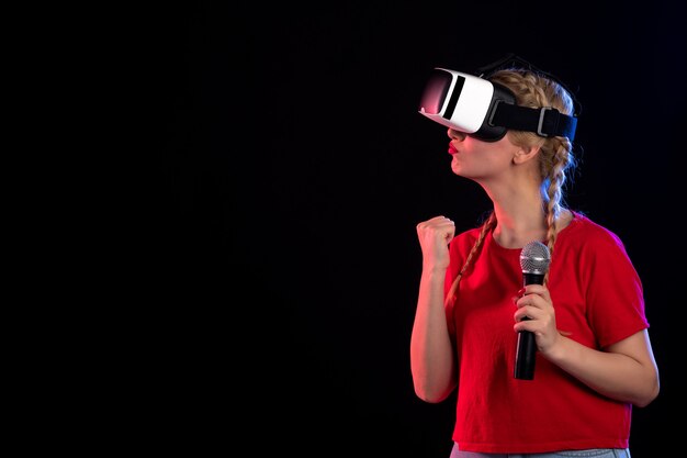 Portrait of young lady playing vr and singing on dark wall