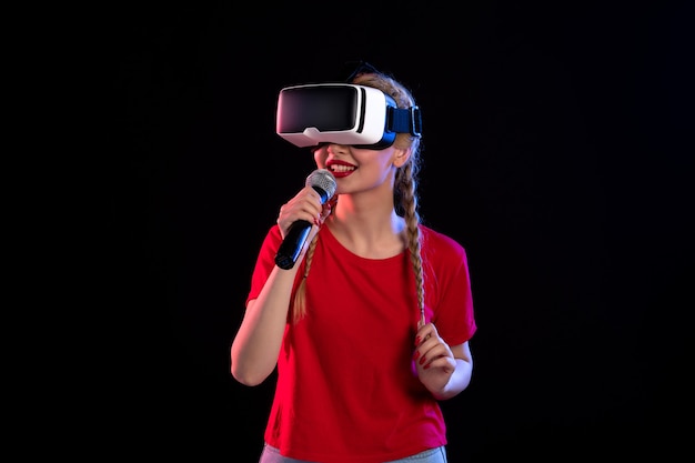 Portrait of young lady playing vr and singing on dark wall