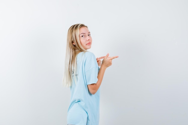 Free photo portrait of young lady pointing to the right side in t-shirt isolated