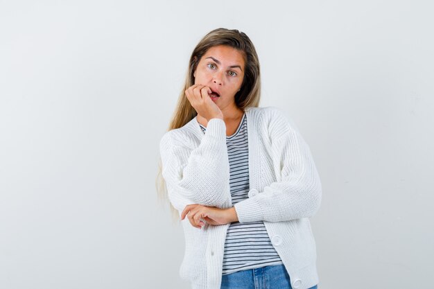 Portrait of young lady propping chin on hand in t-shirt, jacket and looking puzzled front view