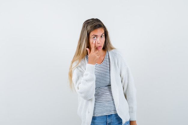 Free photo portrait of young lady pulling down her eyelid in t-shirt, jacket and looking serious front view