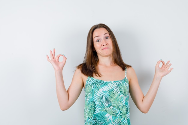 Portrait of young lady showing ok gesture in blouse and looking confident front view