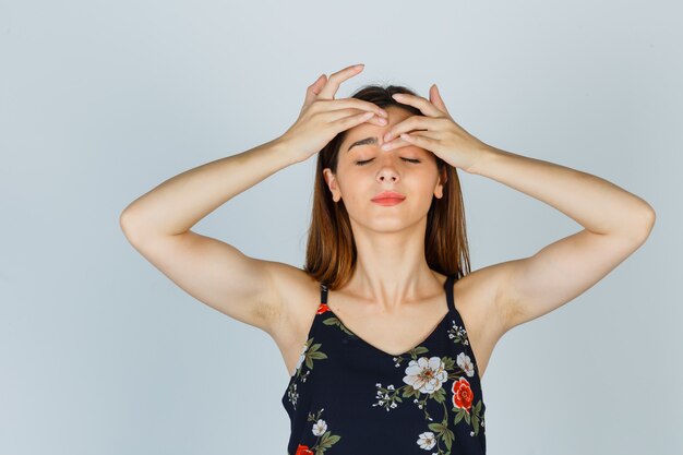 Free photo portrait of young lady squeezing her pimple on forehead in blouse and looking relaxed front view