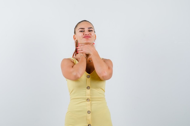 Ritratto di giovane donna che soffre di mal di gola in abito giallo e guardando infastidito vista frontale