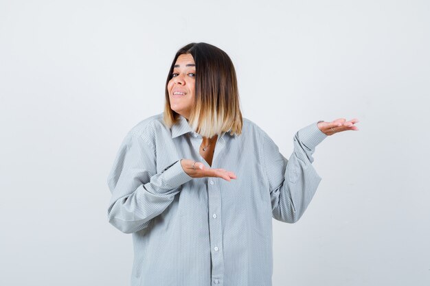 Portrait of young lady welcoming something in oversized shirt and looking happy front view