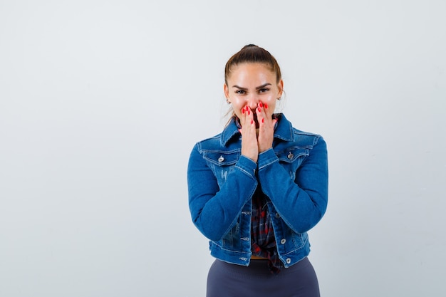 Portrait of young lady with hands on mouth in shirt, jacket and looking cheerful front view