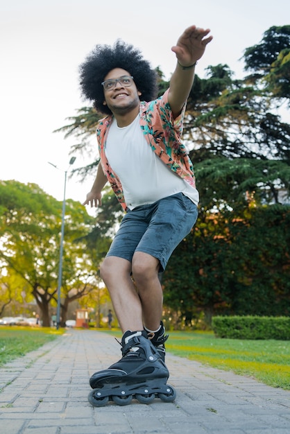 Portrait of young latin man practicing skills while rollerskating outdoors on the street. Sports concept. Urban concept.