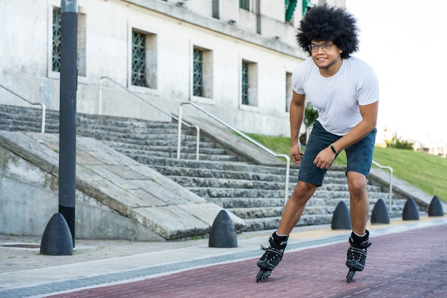 路上で屋外でローラースケートをしている若いラテン系男性の肖像画。スポーツの概念。アーバンコンセプト。