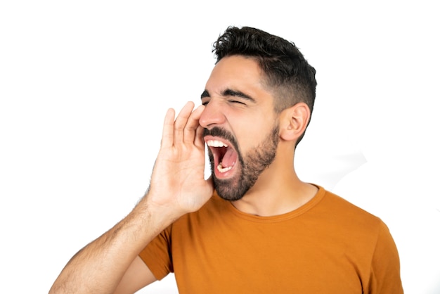 Portrait of young latin man shouting and screaming against white space