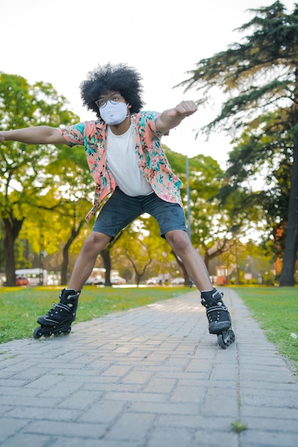 路上で屋外でローラースケートをしながらフェイスマスクを身に着けている若いラテン男性の肖像画