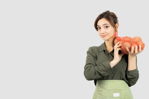 袋にジャガイモを保持している若い素敵な農家の女性の肖像画。高品質の写真